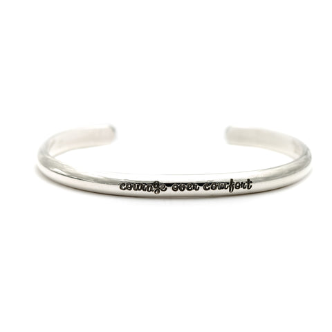 Handmade sterling silver cuff bracelet with the message "courage over comfort".